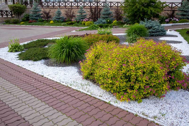Shrub beds with white gravel mulch beside red brick paving, Midstream Estate