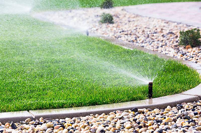Lawn sprinkler watering a lawn beside a pebble bed, Centurion