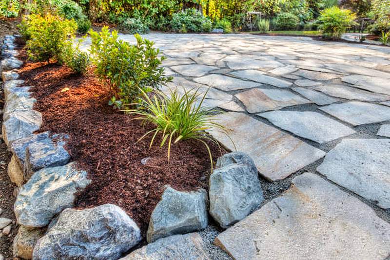 Natural flagstone patio with boulder edging and mulched bed, Irene