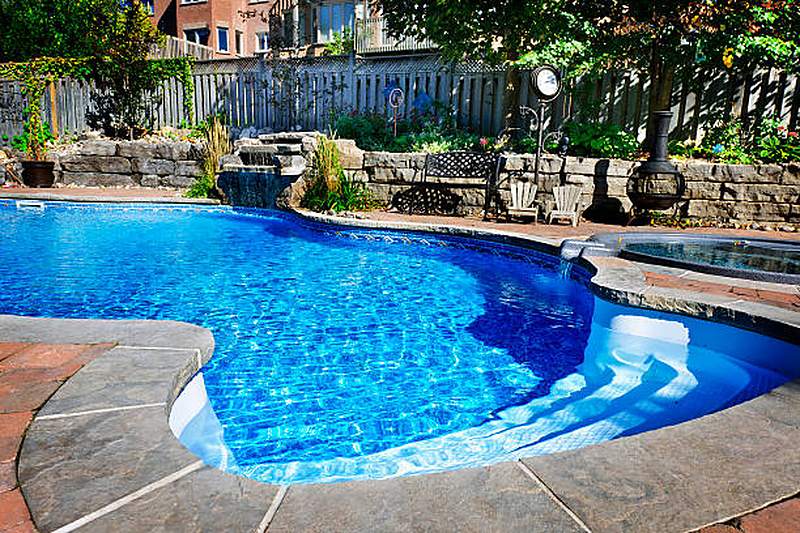 Pool with stone waterfall feature, spa and flagstone surround, Midstream Estate