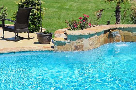 Swimming pool with raised stone wall water feature and patio seating, Waterkloof
